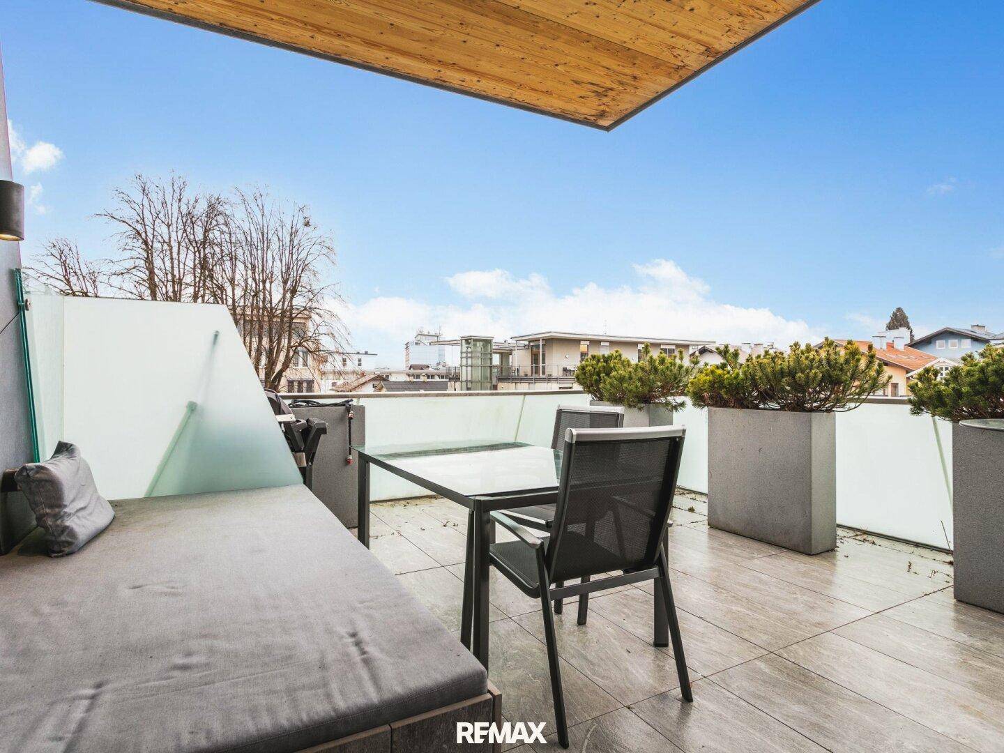 Geräumige Dachterrasse mit Sitzgelegenheiten, Pflanzen und Blick auf die umliegende Bebauung.