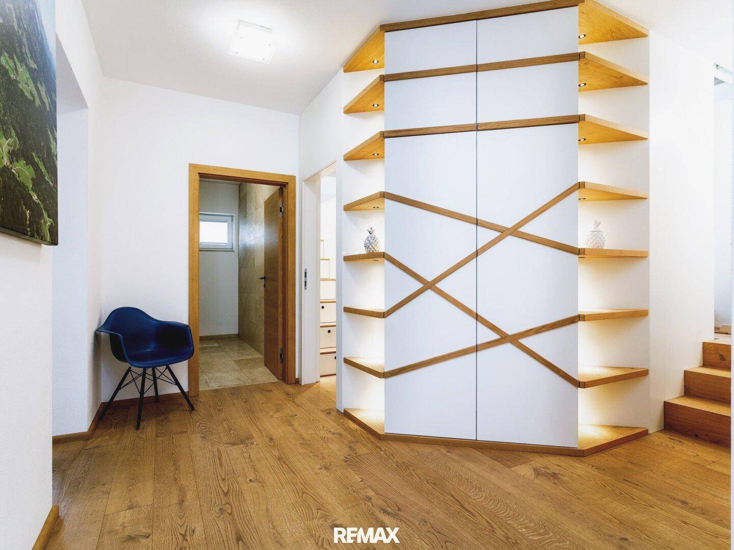 Heller Flur mit maßgefertigten Holzregalen, integrierten Schränken und Holzboden.