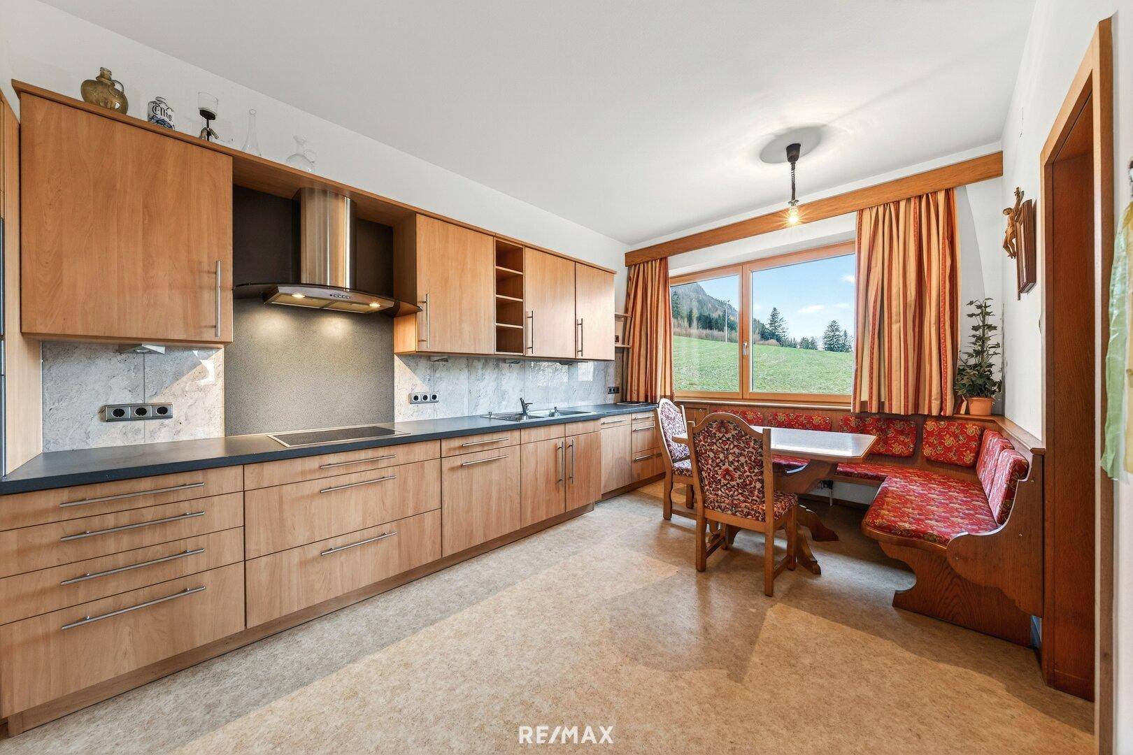 Geräumige Küche im traditionellen Stil mit Holzschränken, Essbereich und Fenster.