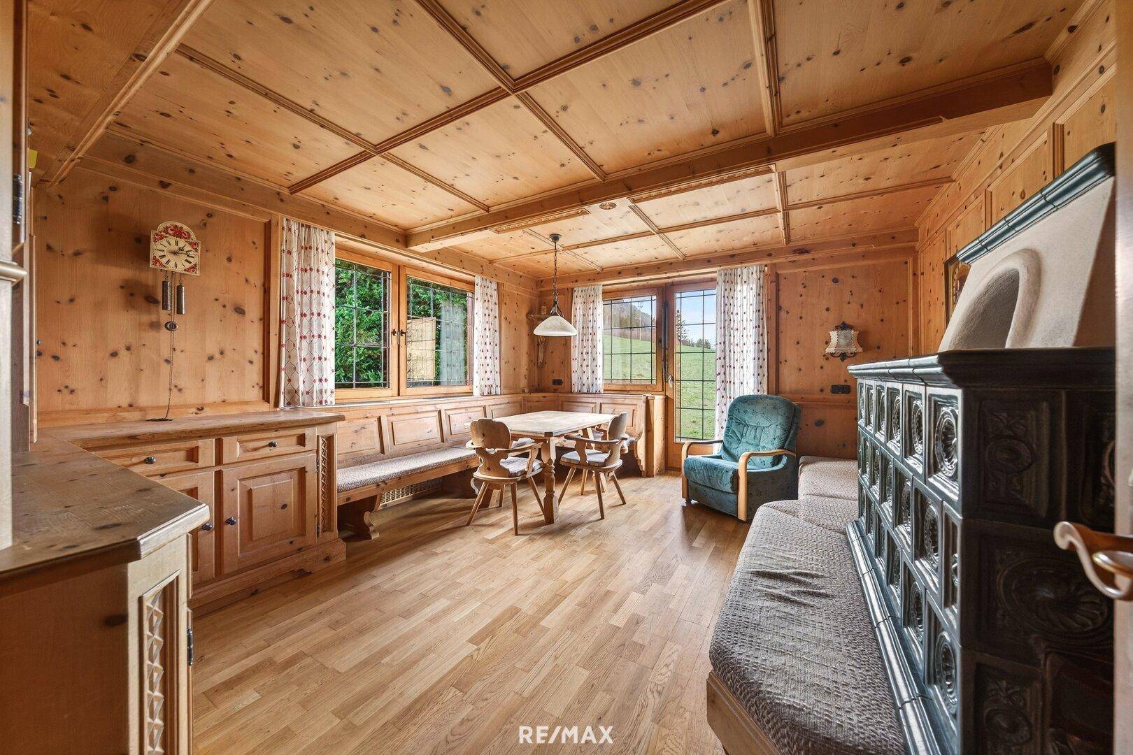 Gemütlicher Wohn- und Essbereich mit Kachelofen, Holzboden und Holzverkleidung.