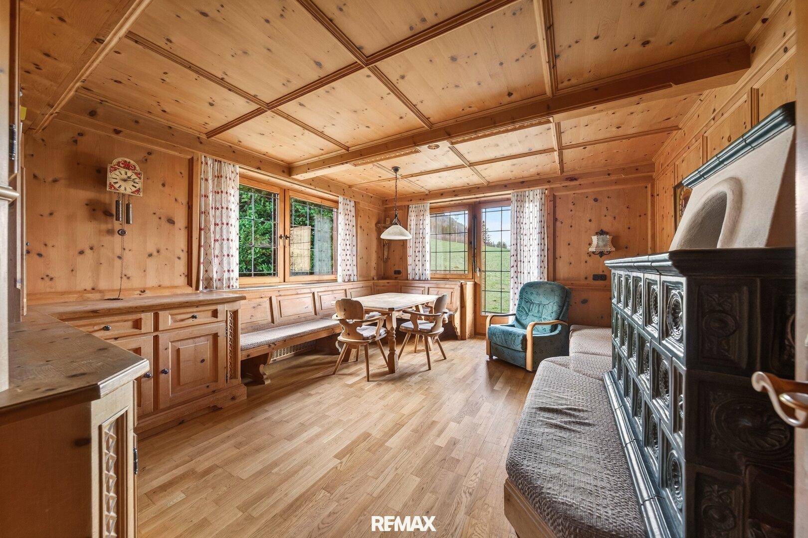 Traditionelles Wohnzimmer mit Holztäfelung, Kachelofen und gemütlicher Sitzecke.