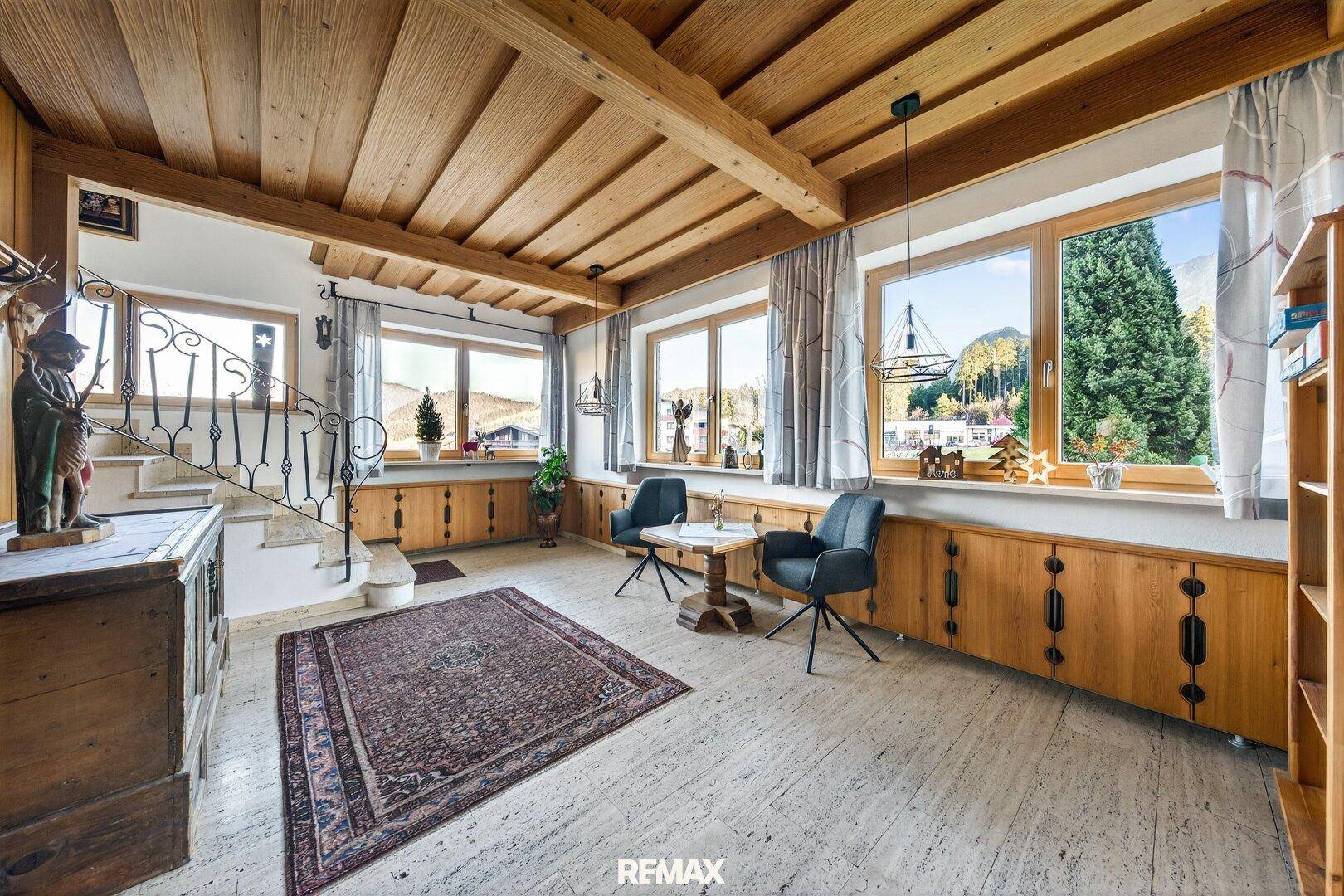 Geräumiger Flur mit Natursteinboden, Holzdecke und einer eleganten Treppe.