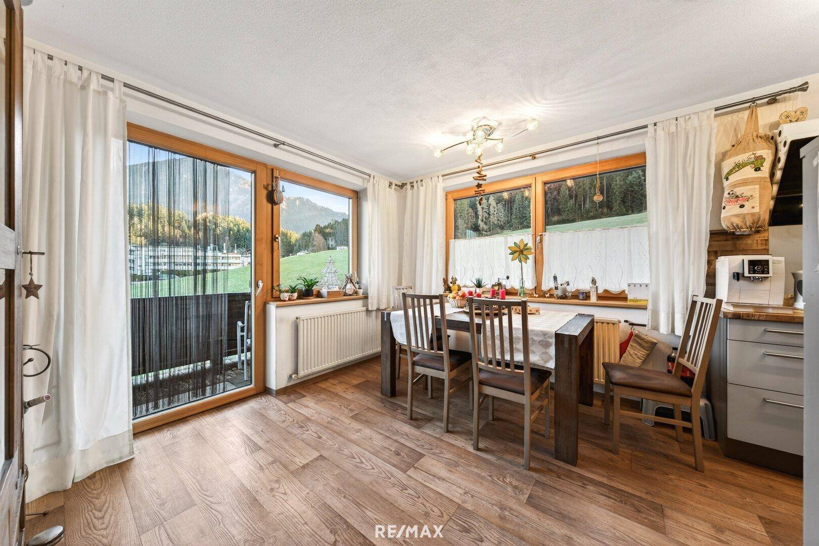 Heller Essbereich mit Holzboden und großem Fenster mit Blick auf die Landschaft.