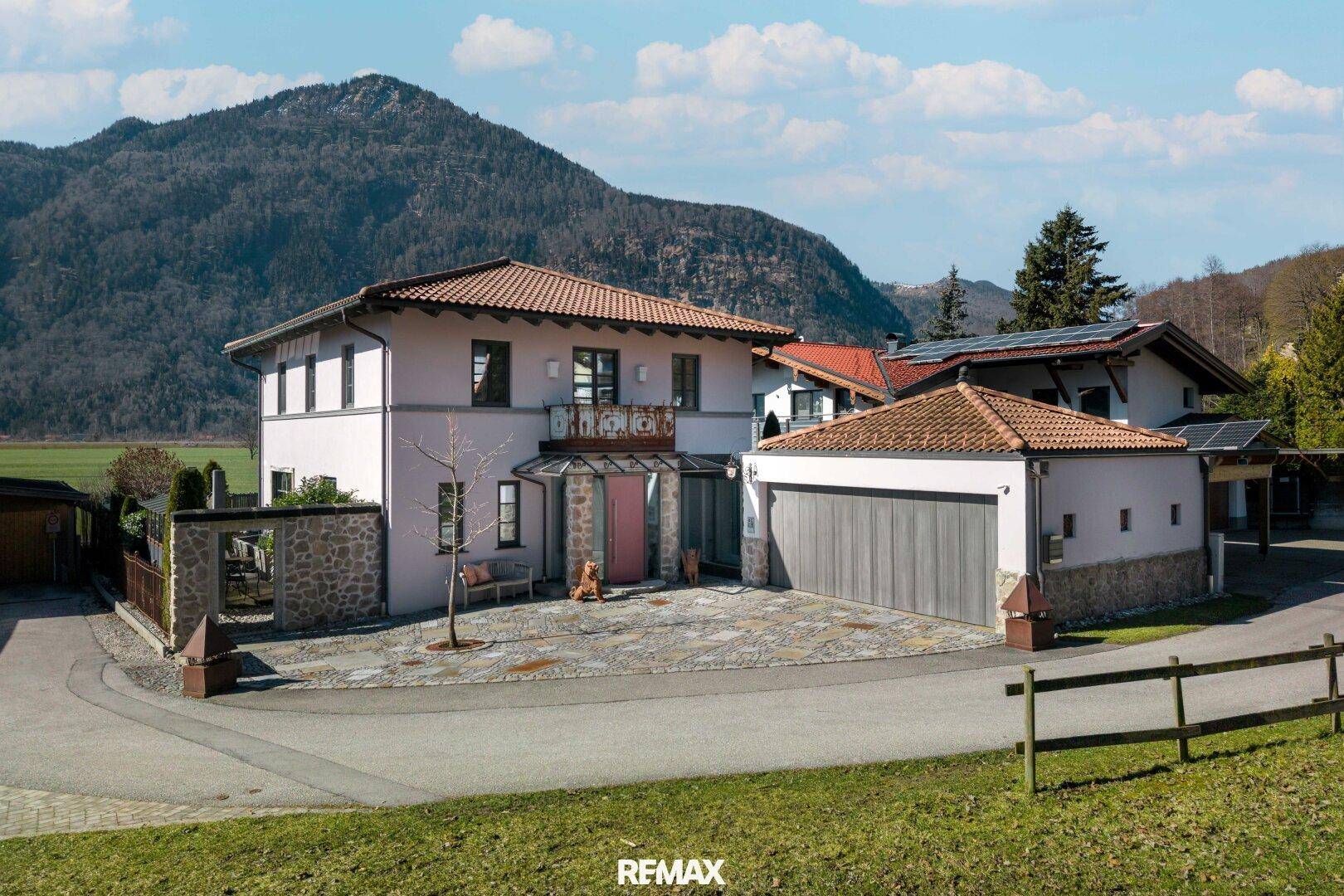 Elegantes Wohnhaus mit Doppelgarage, gepflasterter Auffahrt und Bergblick.