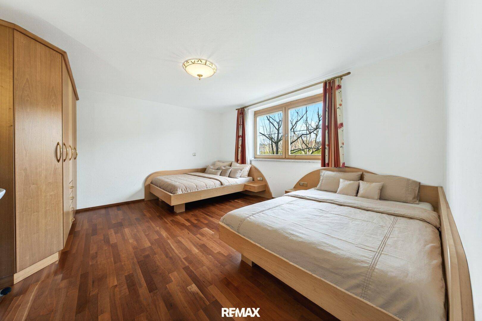Schlafzimmer mit zwei Einzelbetten, Holzschrank und Holzboden, ideal für Gäste oder Kinder.
