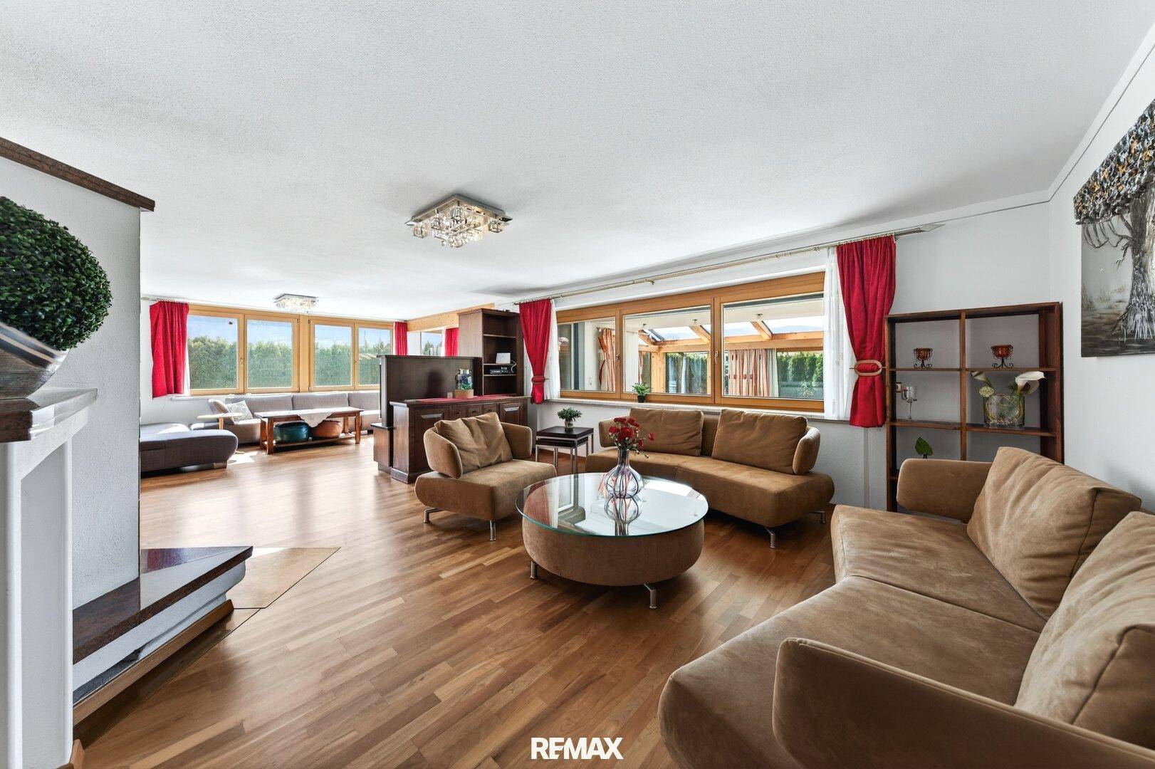 Geräumiges Wohnzimmer mit Holzboden, bequemen Sofas und vielen Fenstern mit Ausblick.