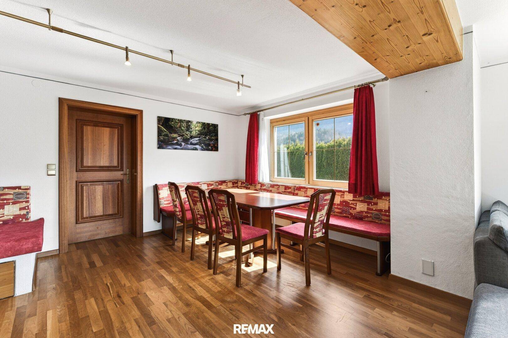 Essbereich mit Holztisch, Stühlen und traditioneller Eckbank am Fenster mit Blick ins Grüne.