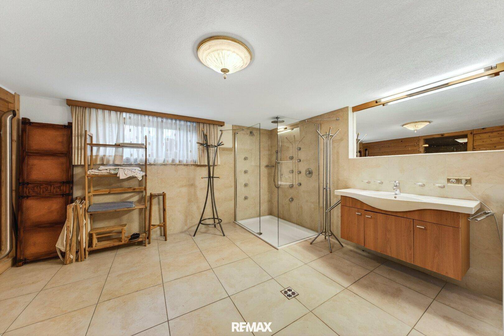 Modernes Badezimmer mit großer begehbarer Dusche und beigefarbenen Fliesen.