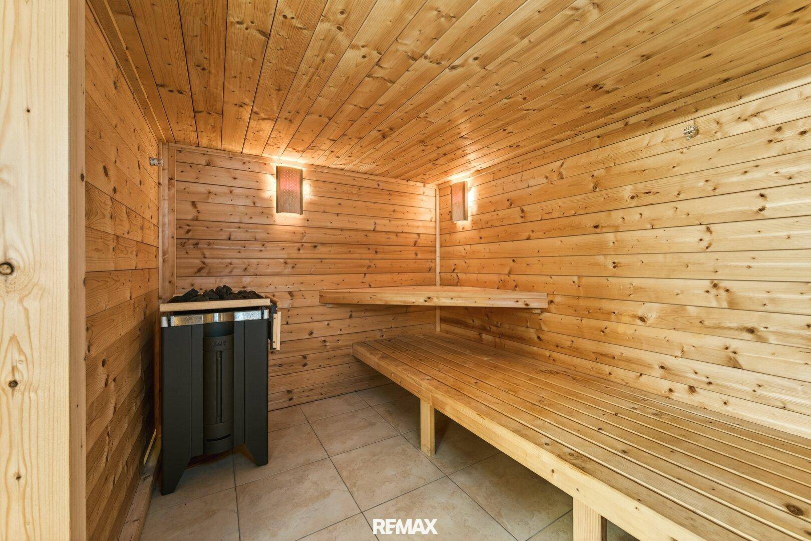 Helle Holzsauna mit zwei Bänken und modernem Saunaofen, ideal zur Entspannung.