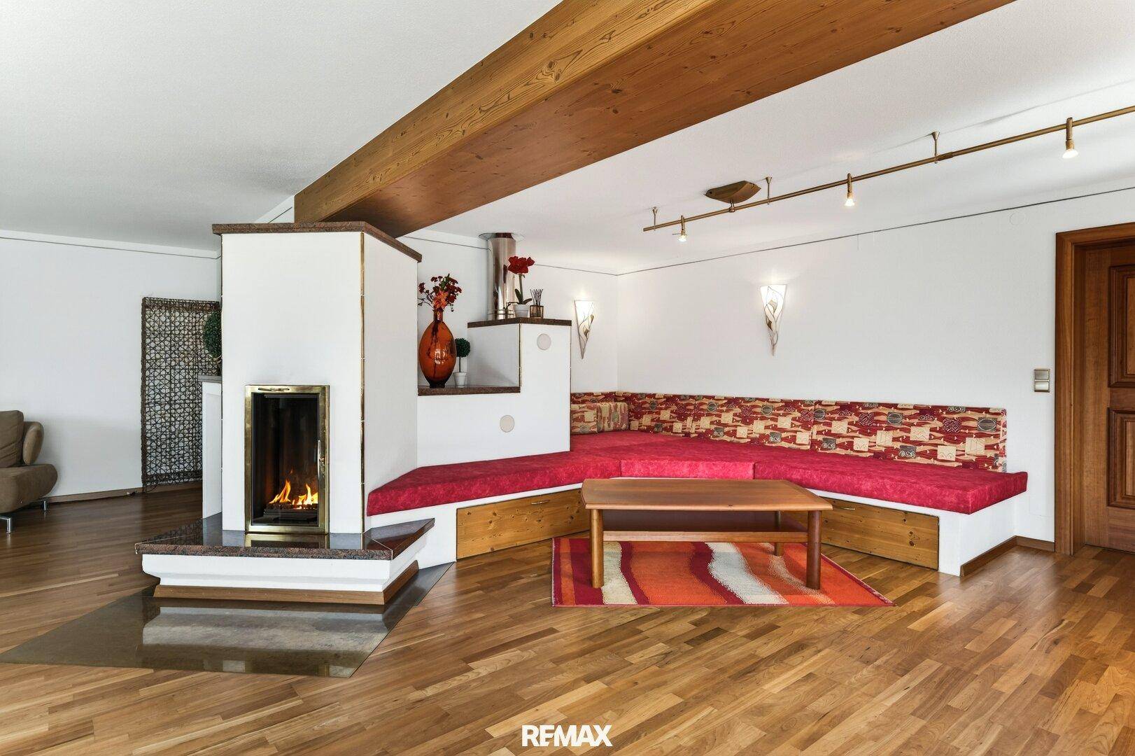 Traditioneller Wohnbereich mit Kamin, Holzboden und gemütlicher Eckbank im alpinen Stil.