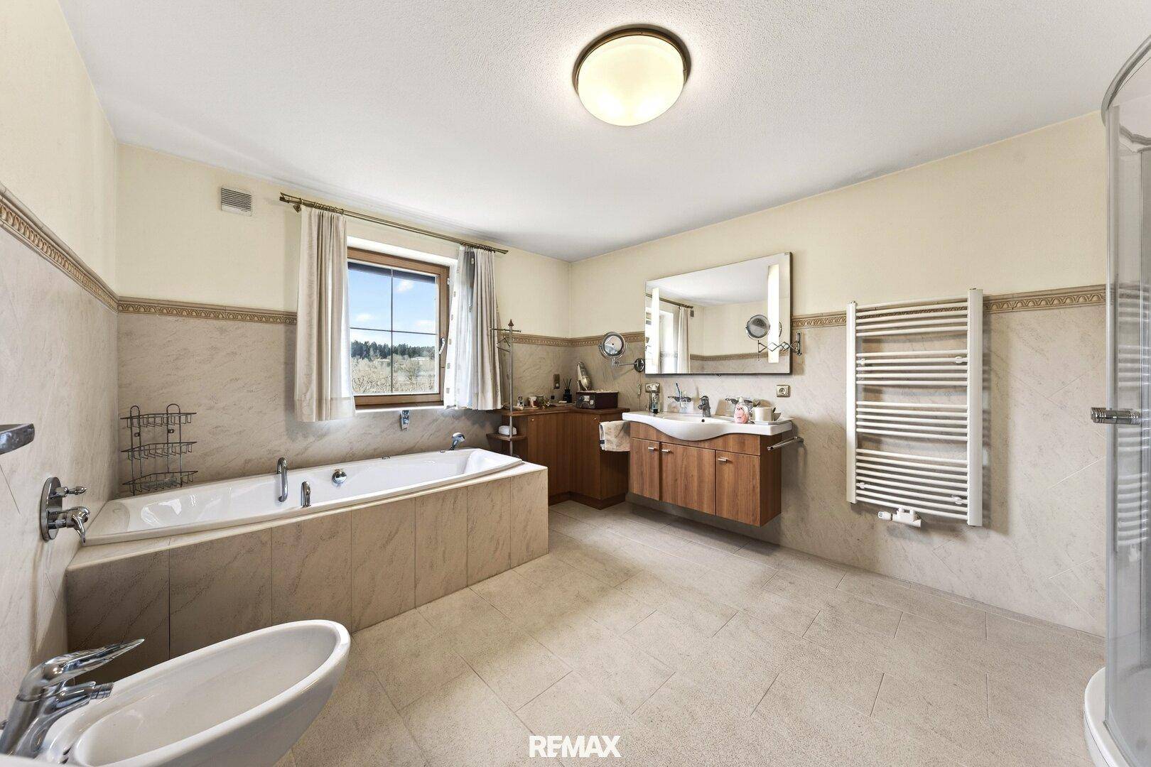 Geräumiges Badezimmer mit Badewanne, Dusche, Bidet und beheiztem Handtuchhalter.