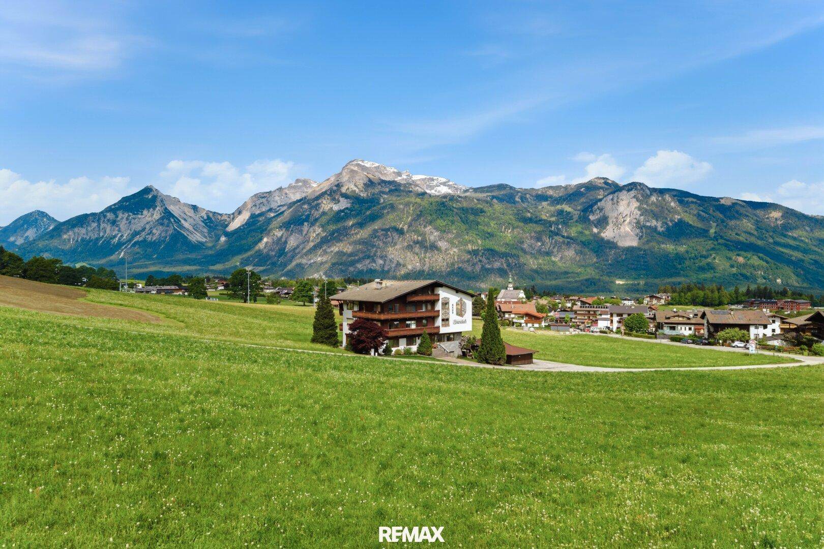 Panoramablick auf ein charmantes Haus in alpiner Landschaft mit majestätischen Bergen im Hintergrund.
