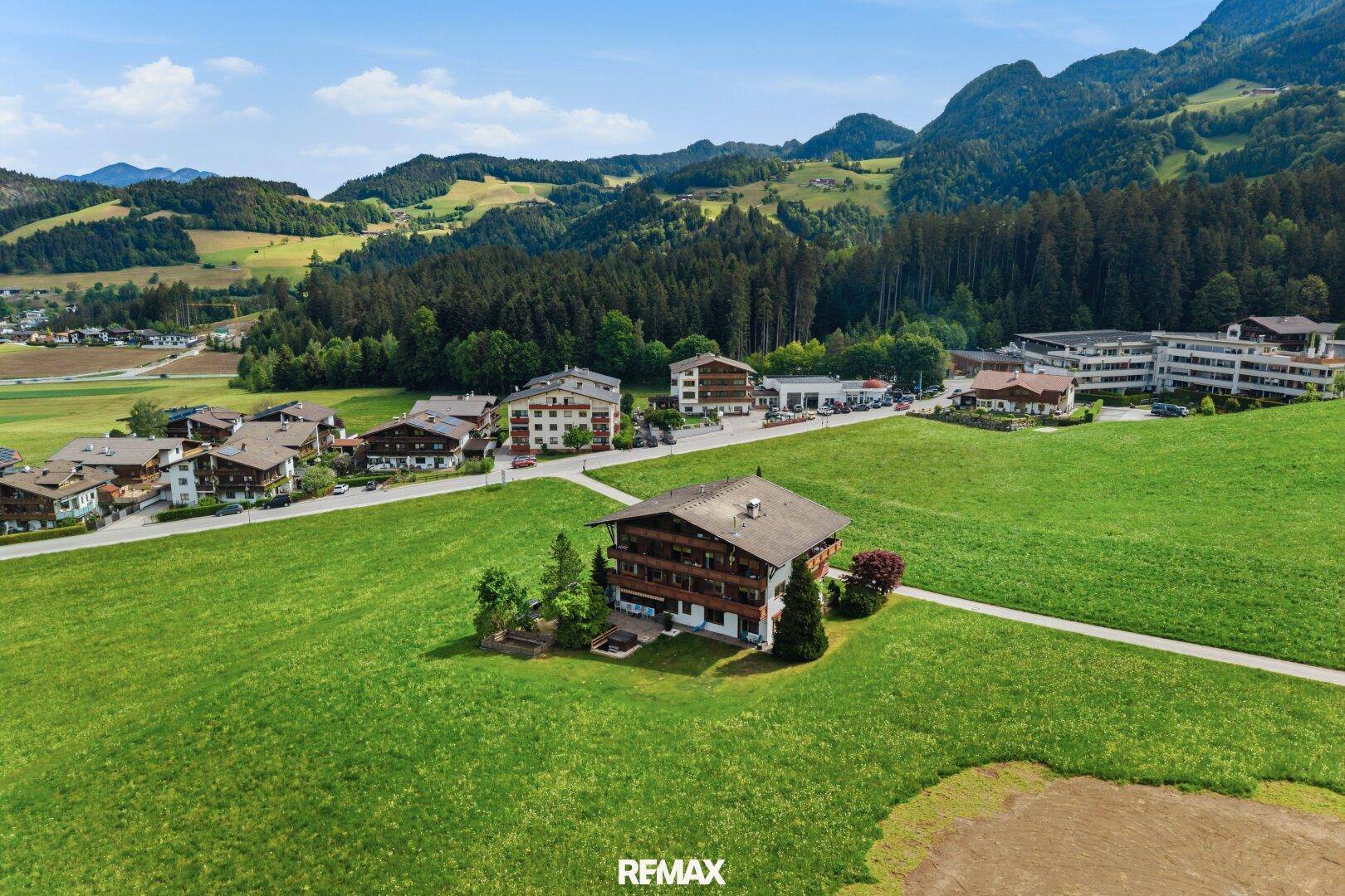 Luftaufnahme eines traditionellen Gebäudes in einer malerischen Berglandschaft mit umliegenden Häusern.