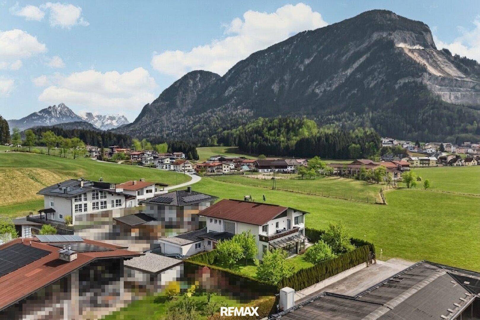 Panoramablick auf ein malerisches Dorf in einer grünen Berglandschaft mit vielen Häusern und Dächern.