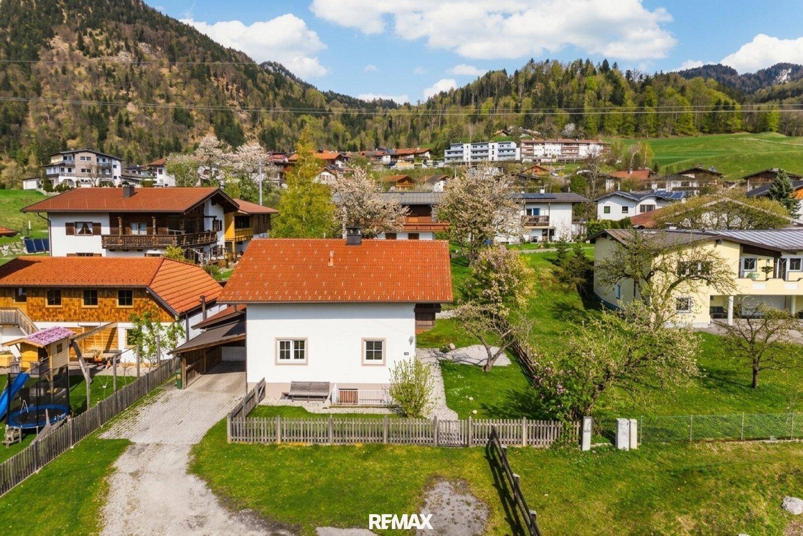 Vorderansicht des Hauses mit Einfahrt und Vorgarten, eingebettet in eine ländliche Umgebung mit Bergblick.