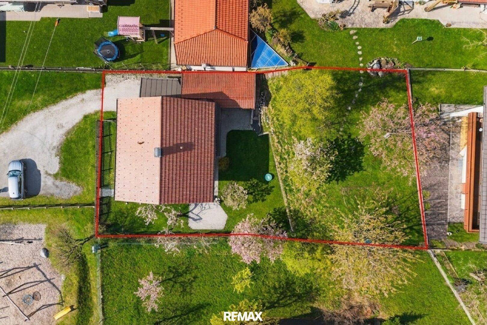 Luftaufnahme des Grundstücks mit roter Umrandung, zeigt das Haus, die Einfahrt und die umliegenden Grünflächen.