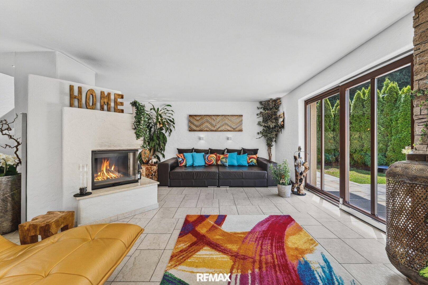 Gemütliches Wohnzimmer mit Kamin, großem Sofa und Zugang zur Terrasse oder Garten.