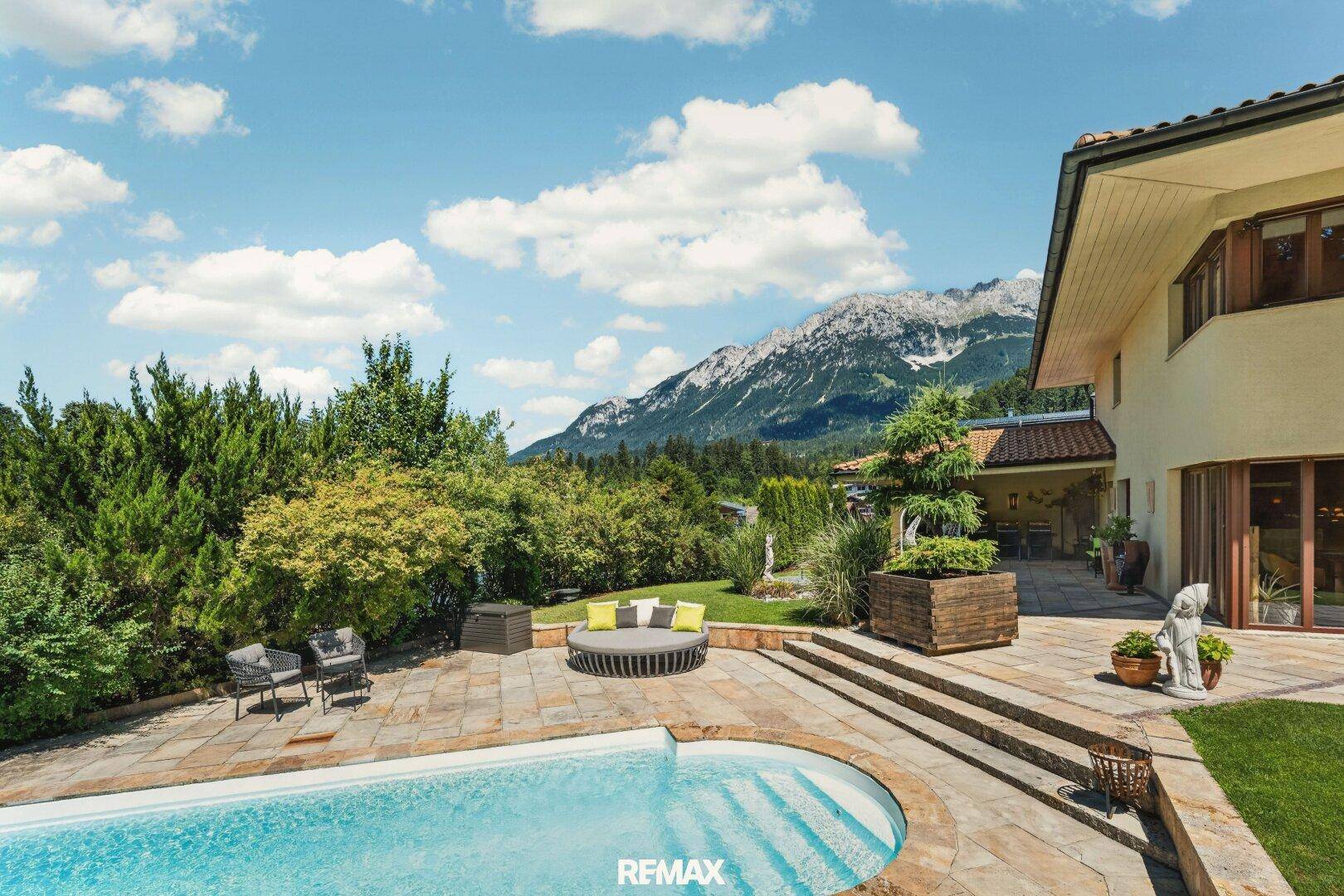 Weitläufiger Gartenbereich mit Pool, Sonnenterrasse und beeindruckendem Bergblick.