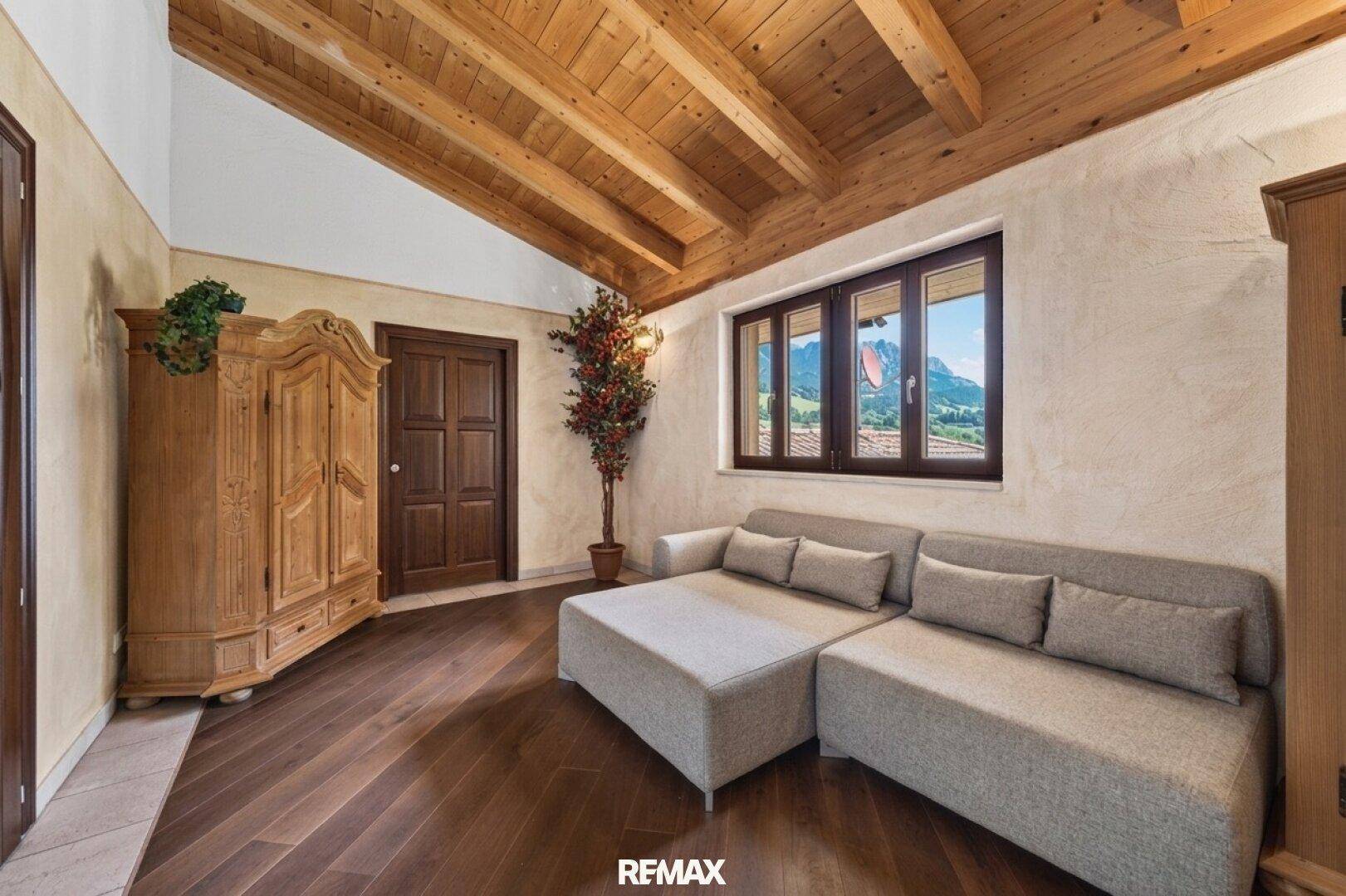 Gemütliches Zimmer im Dachgeschoss mit Holzbalkendecke, Sofa und Bergblick.