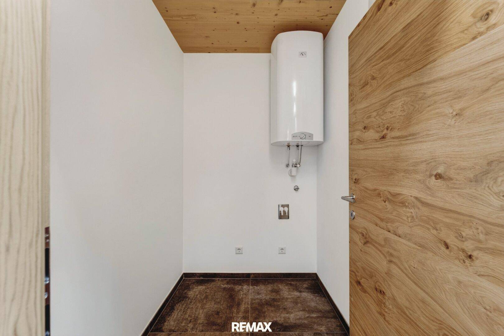 Praktischer Hauswirtschaftsraum mit Warmwasserboiler und Fliesenboden.