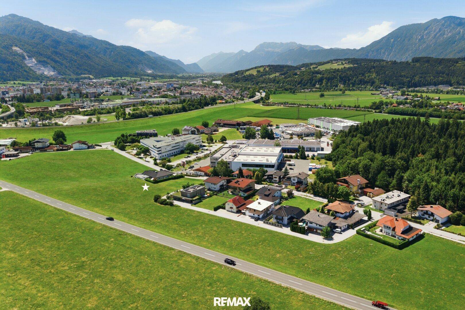 Panoramablick aus der Vogelperspektive auf eine Siedlung, Felder und die umliegende Berglandschaft.