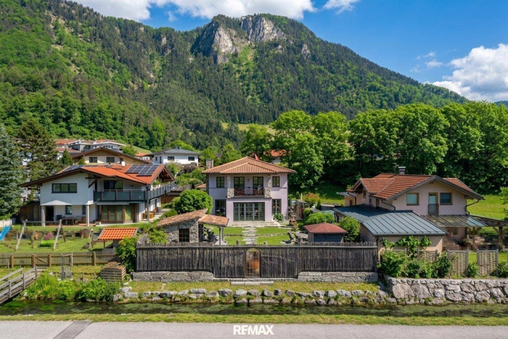 Großzügiges Anwesen in alpiner Umgebung mit mehreren Gebäuden und weitläufigem Garten.