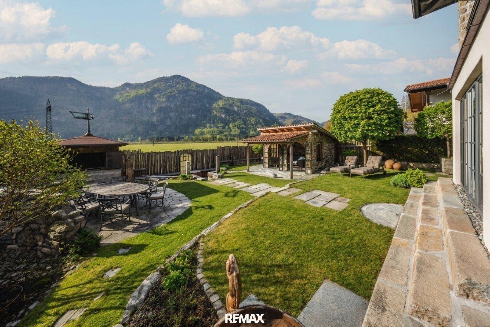 Weitläufiger Gartenbereich mit Rasenflächen, Steinterrassen und einem charmanten Gartenhaus.