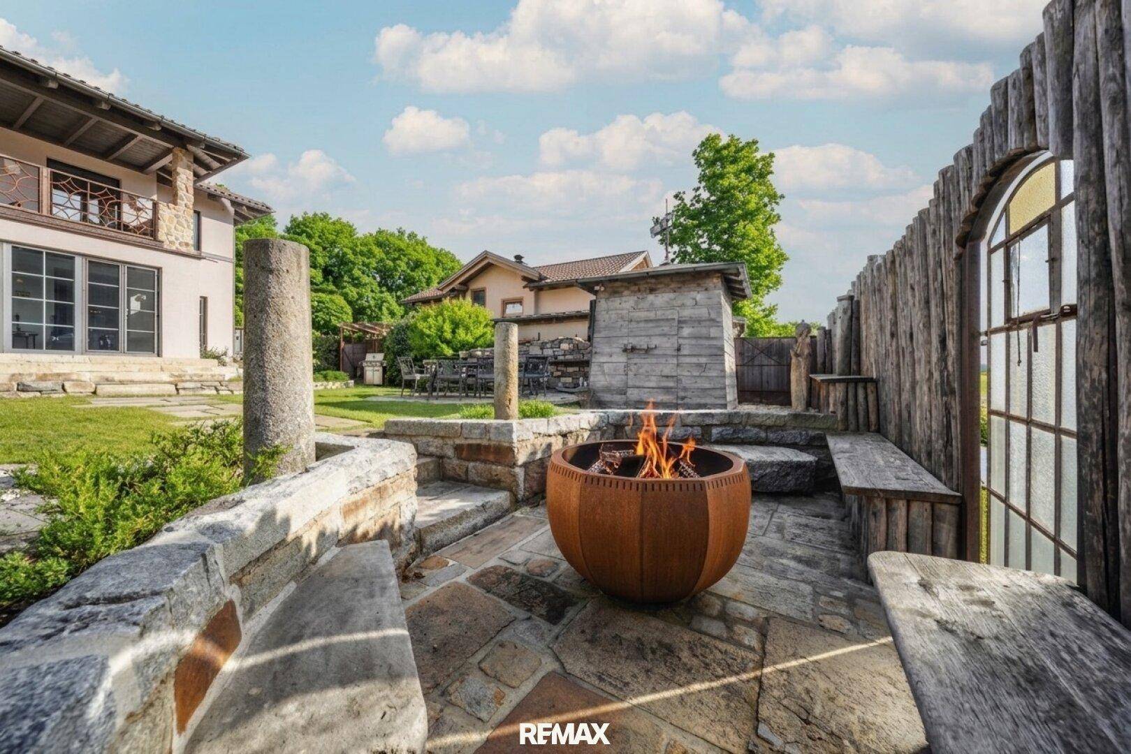 Gemütlicher Terrassenbereich mit Feuerstelle und Steinbänken, ideal für Abende im Freien.