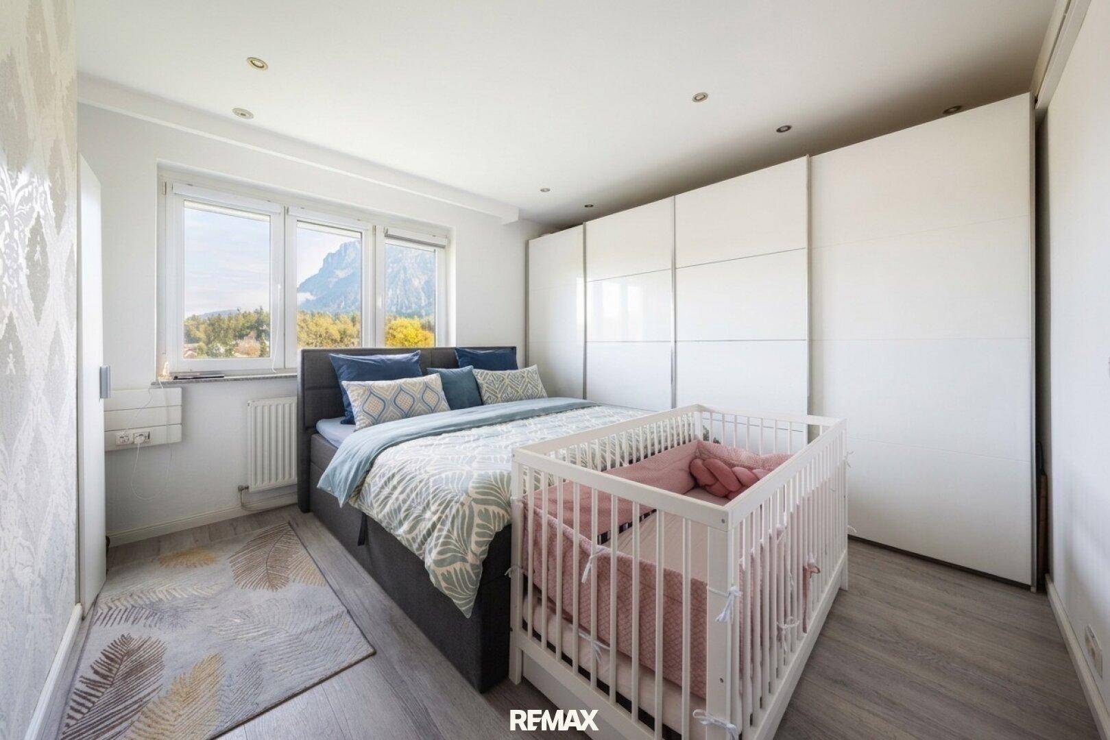 Gemütliches Schlafzimmer mit Doppelbett, Babybett, Einbauschränken und Bergblick.