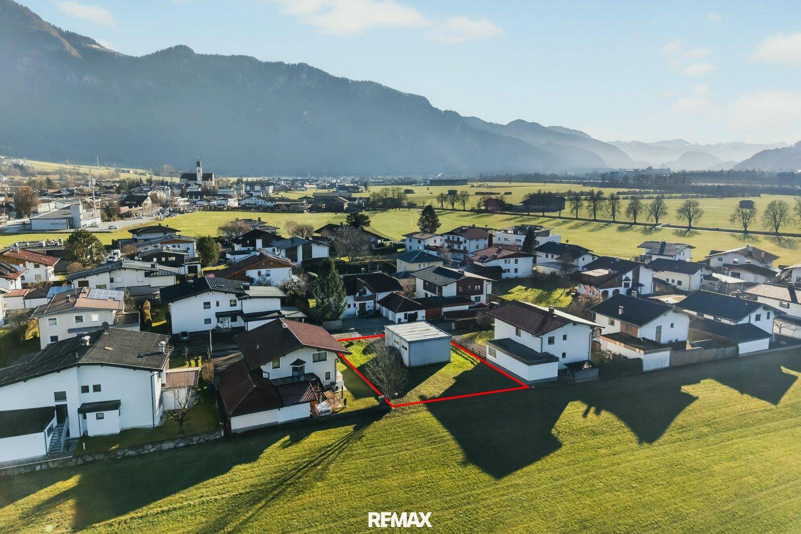 Weitläufige Luftansicht des Grundstücks, umgeben von grünen Feldern und einer malerischen Bergkette.