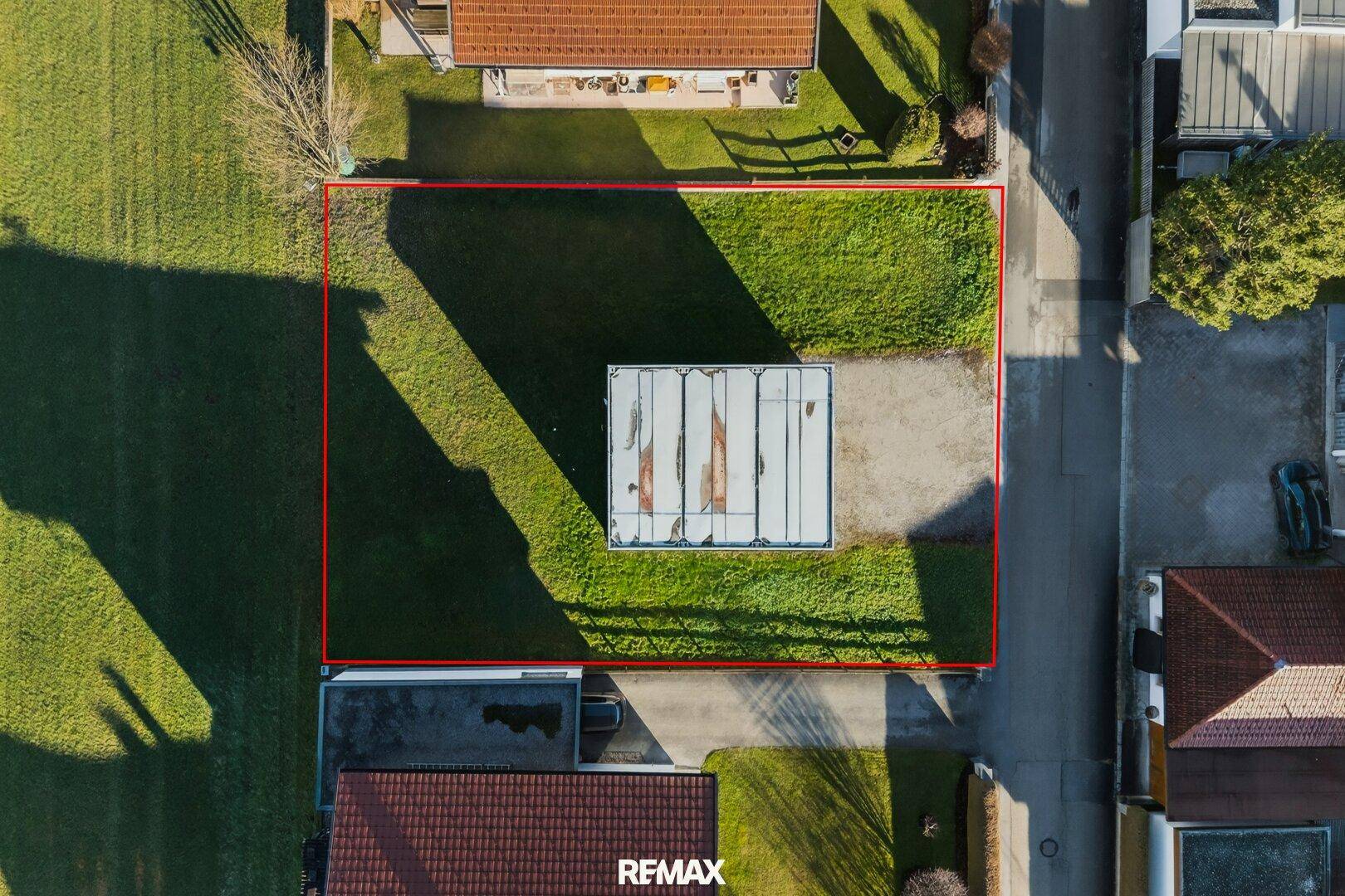 Direkte Draufsicht auf das rechteckige Grundstück mit einem Gebäude und angrenzender Straße.