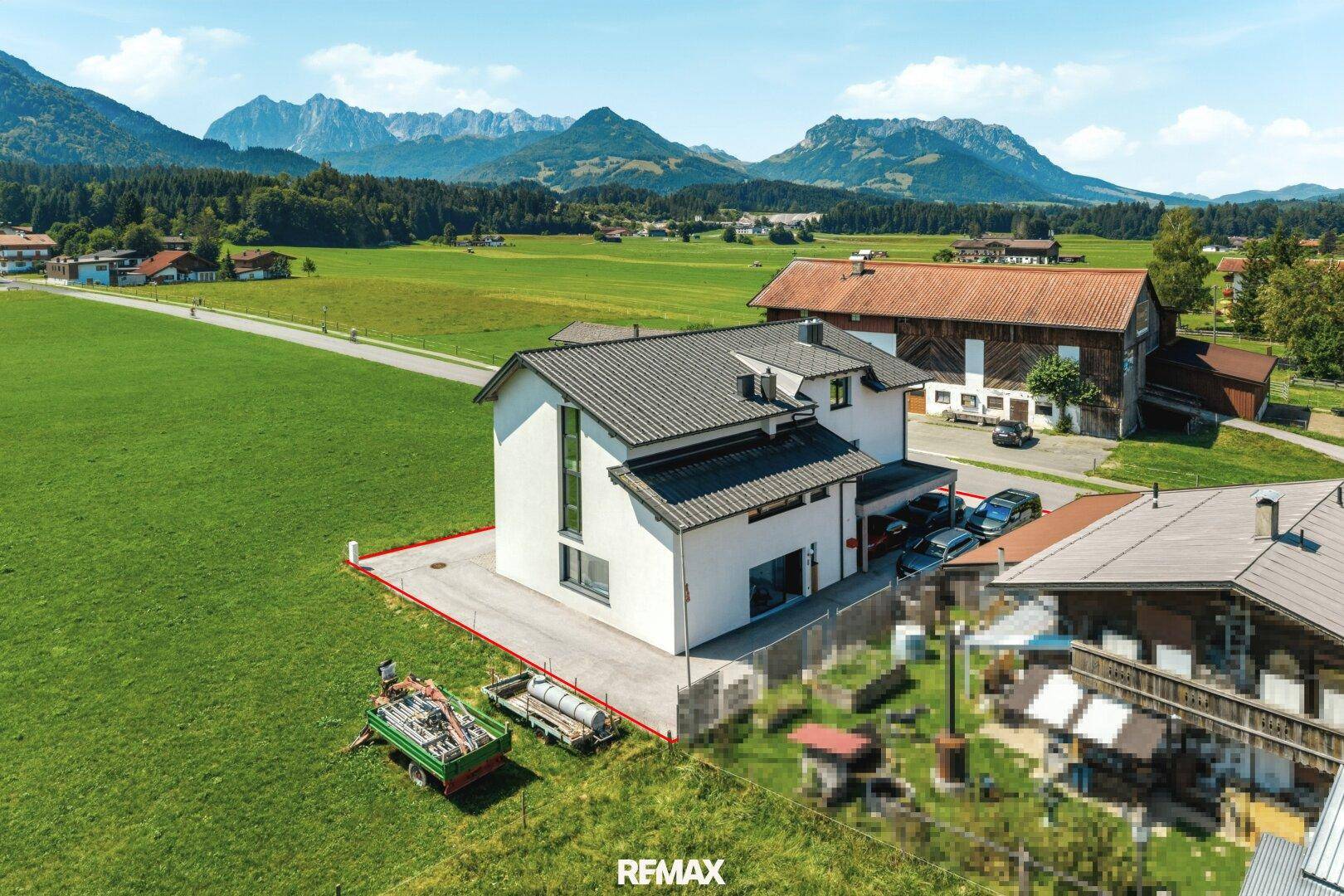 Panoramablick auf das moderne Haus mit Photovoltaikanlage und die umliegende Berglandschaft.