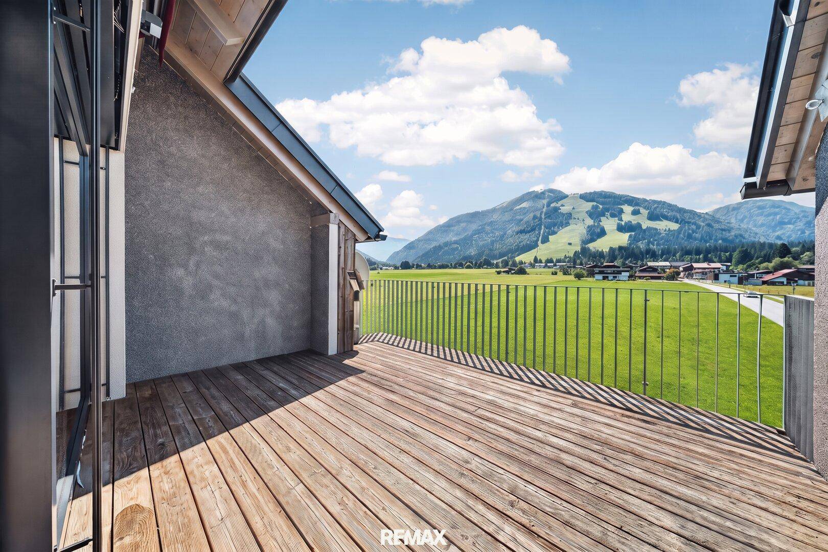 Große Holzterrasse mit Geländer bietet einen weiten Blick auf die umliegende Berglandschaft.