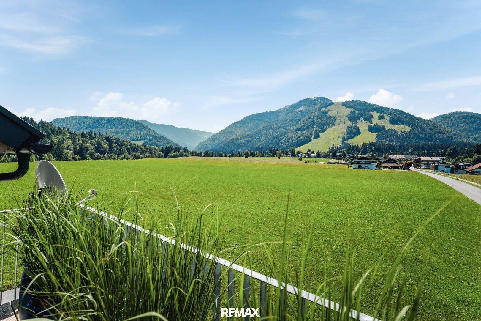 Weitläufiger Blick über grüne Wiesen und die beeindruckende Berglandschaft von der Immobilie.