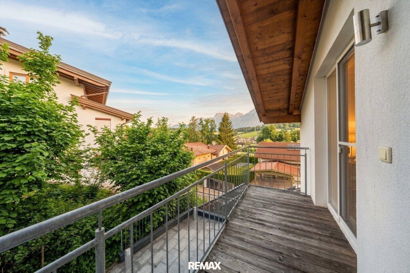 Großer Balkon mit Holzbelag, Metallgeländer und Blick auf die umliegende Landschaft.