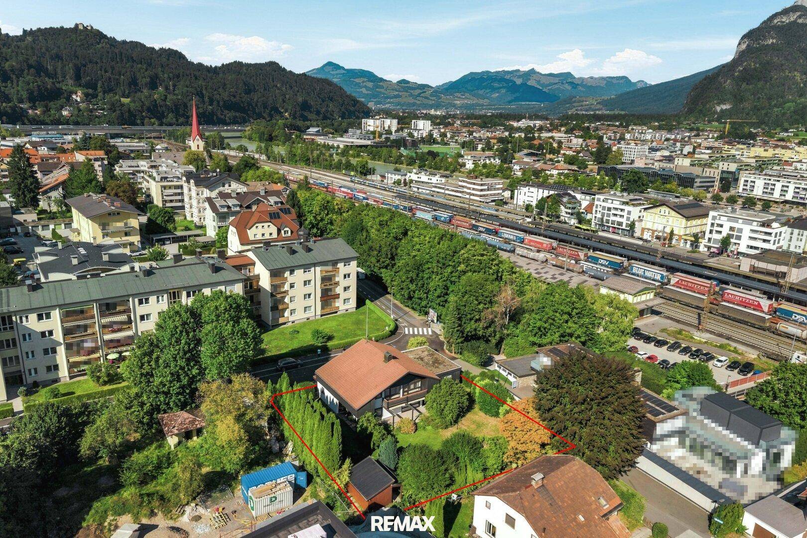 Panoramablick auf das Haus und die Umgebung, mit Bergen, Stadt und Bahnanlagen im Hintergrund.