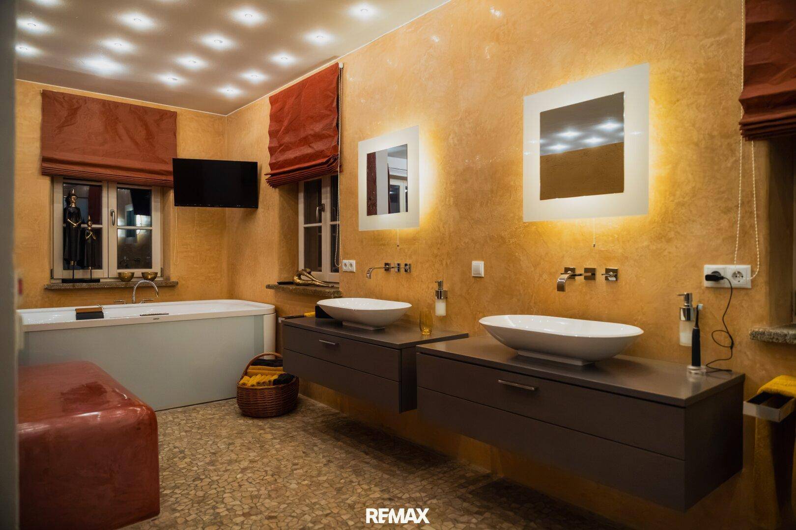 Modernes Badezimmer mit Doppelwaschbecken, freistehender Badewanne und indirekter Beleuchtung.