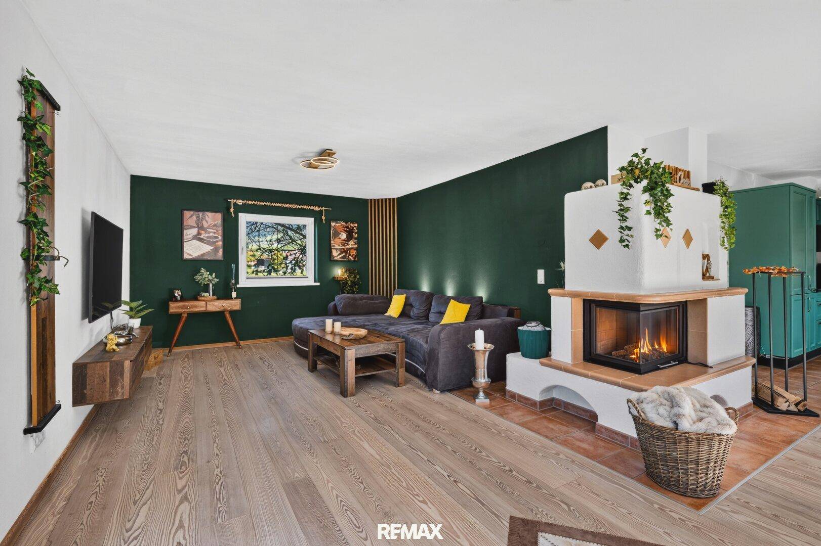 Gemütliches Wohnzimmer mit Kamin, Holzboden und dunklen Akzentwänden.