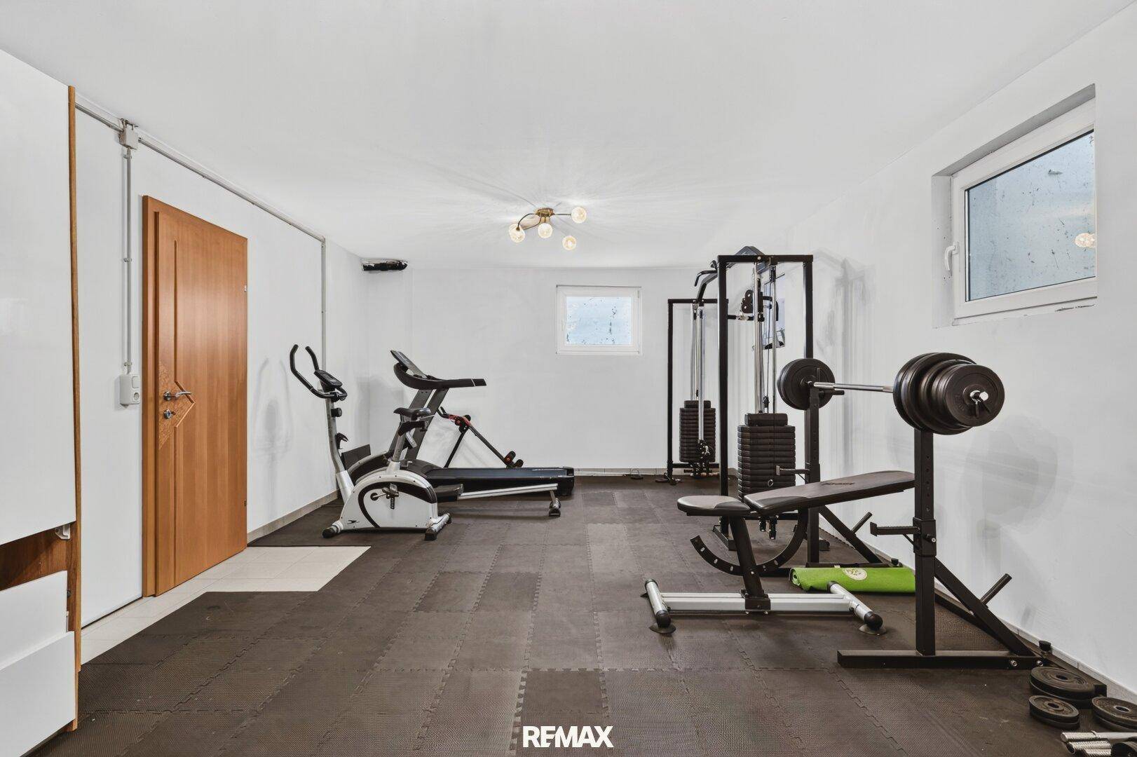 Geräumiger Fitnessraum im Untergeschoss mit Sportgeräten und Fenster.