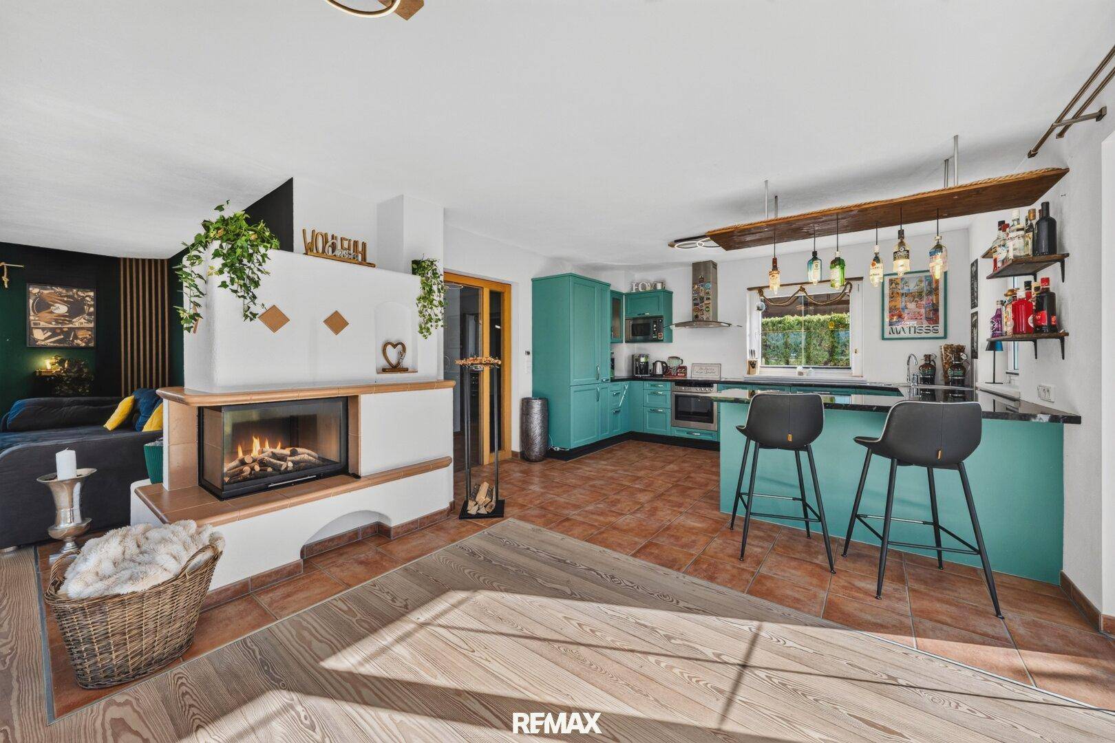 Offener Wohn- und Essbereich mit Kamin, moderner Küche und Zugang zum Garten.
