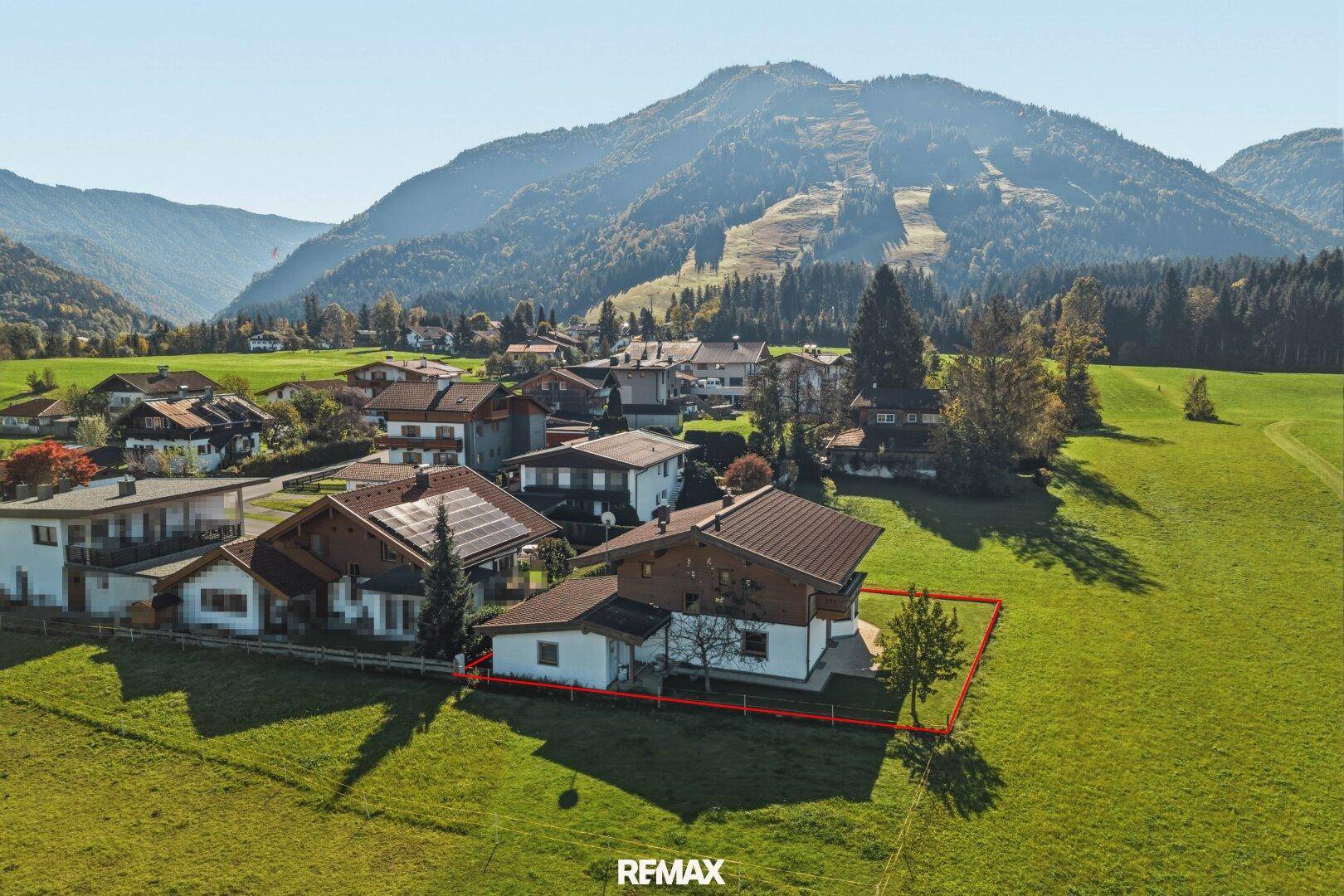 Luftaufnahme eines charmanten Hauses in alpiner Umgebung mit großem Grundstück.