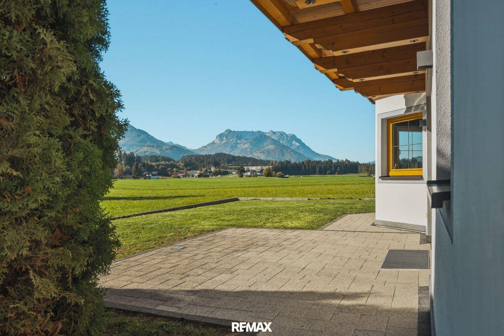 Gepflasterte Terrasse mit Blick auf die umliegende grüne Landschaft und Berge.
