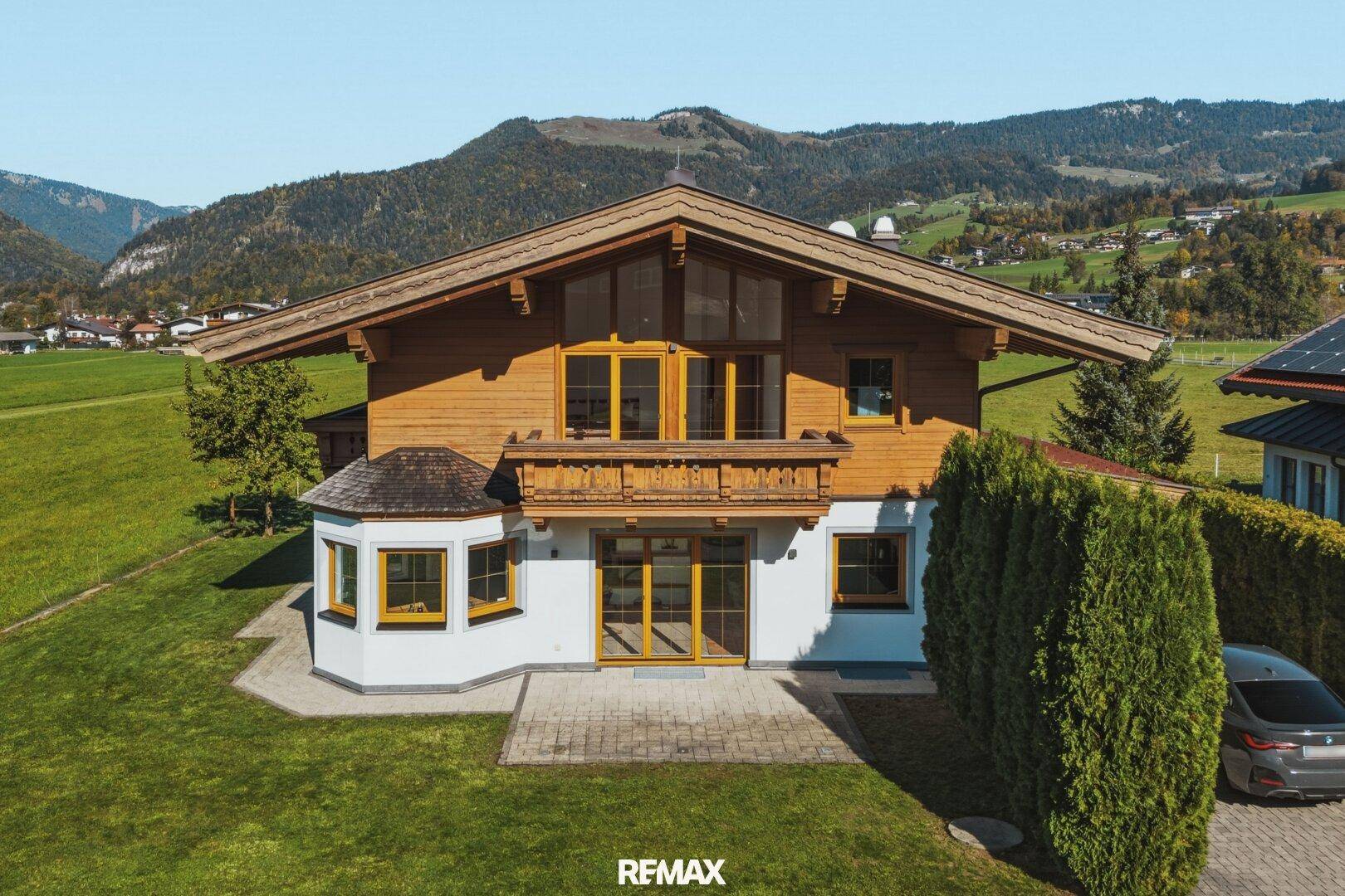 Traditionelles Holzhaus mit weißer Fassade, Balkonen und großen Fenstern.