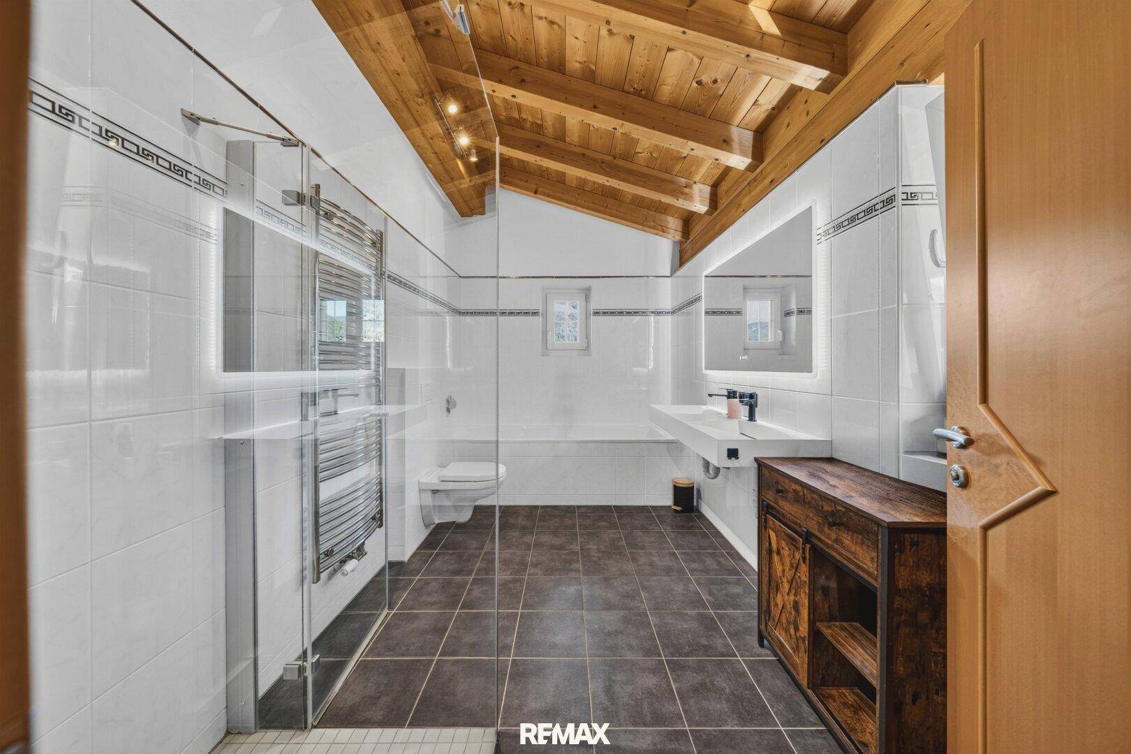 Modernes Badezimmer mit begehbarer Dusche, Holzbalkendecke und eleganten Fliesen.
