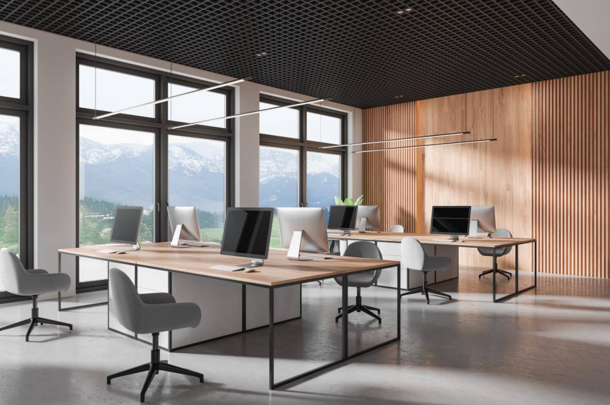 Modernes Großraumbüro mit Bergblick, großen Fenstern, Holzvertäfelung und minimalistischen Arbeitsplätzen.
