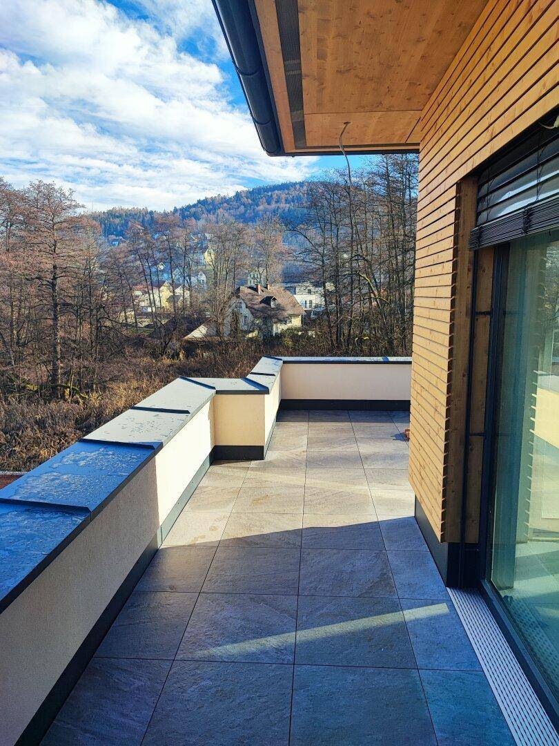 Geräumige Terrasse mit Fliesenboden und Blick auf die bewaldete Hügellandschaft.