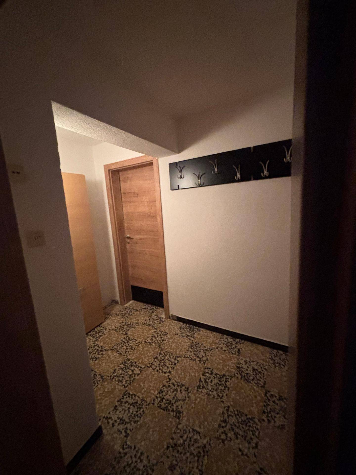 Flur mit gemustertem Fliesenboden und einer Garderobe an der Wand.