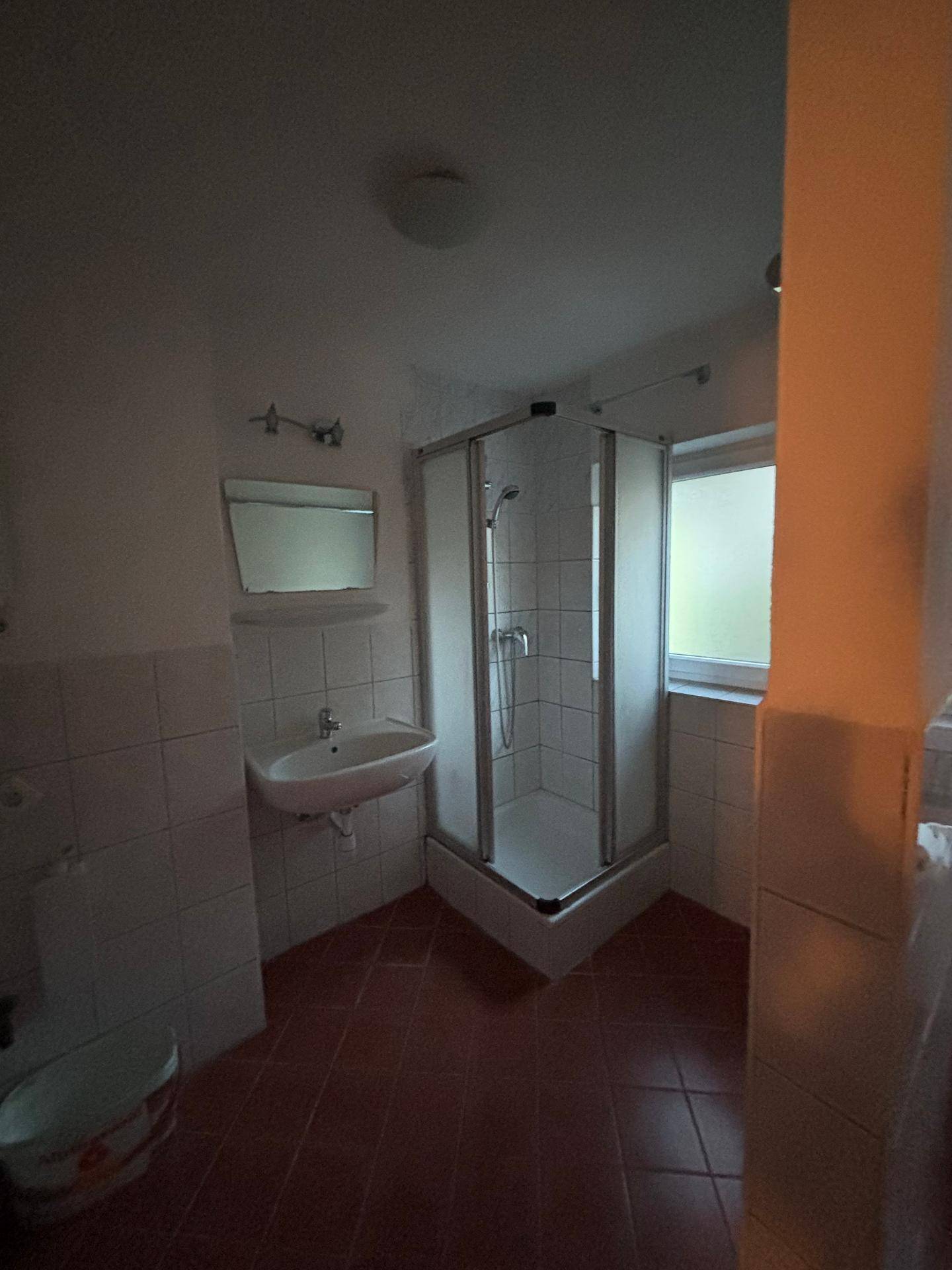 Detailansicht der Duschkabine und des Waschbeckens im Badezimmer.
