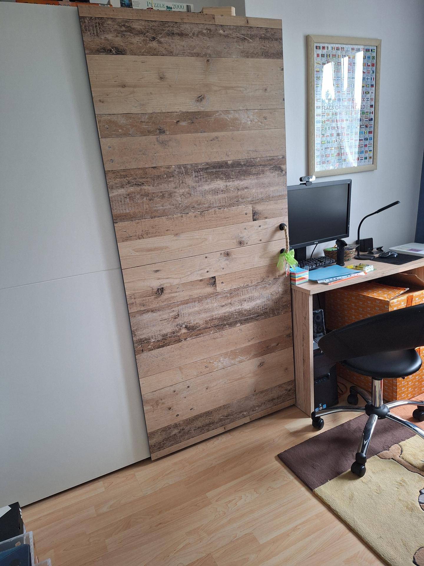 Arbeitszimmer mit Schreibtisch, Computer und einer dekorativen Holzwandverkleidung.