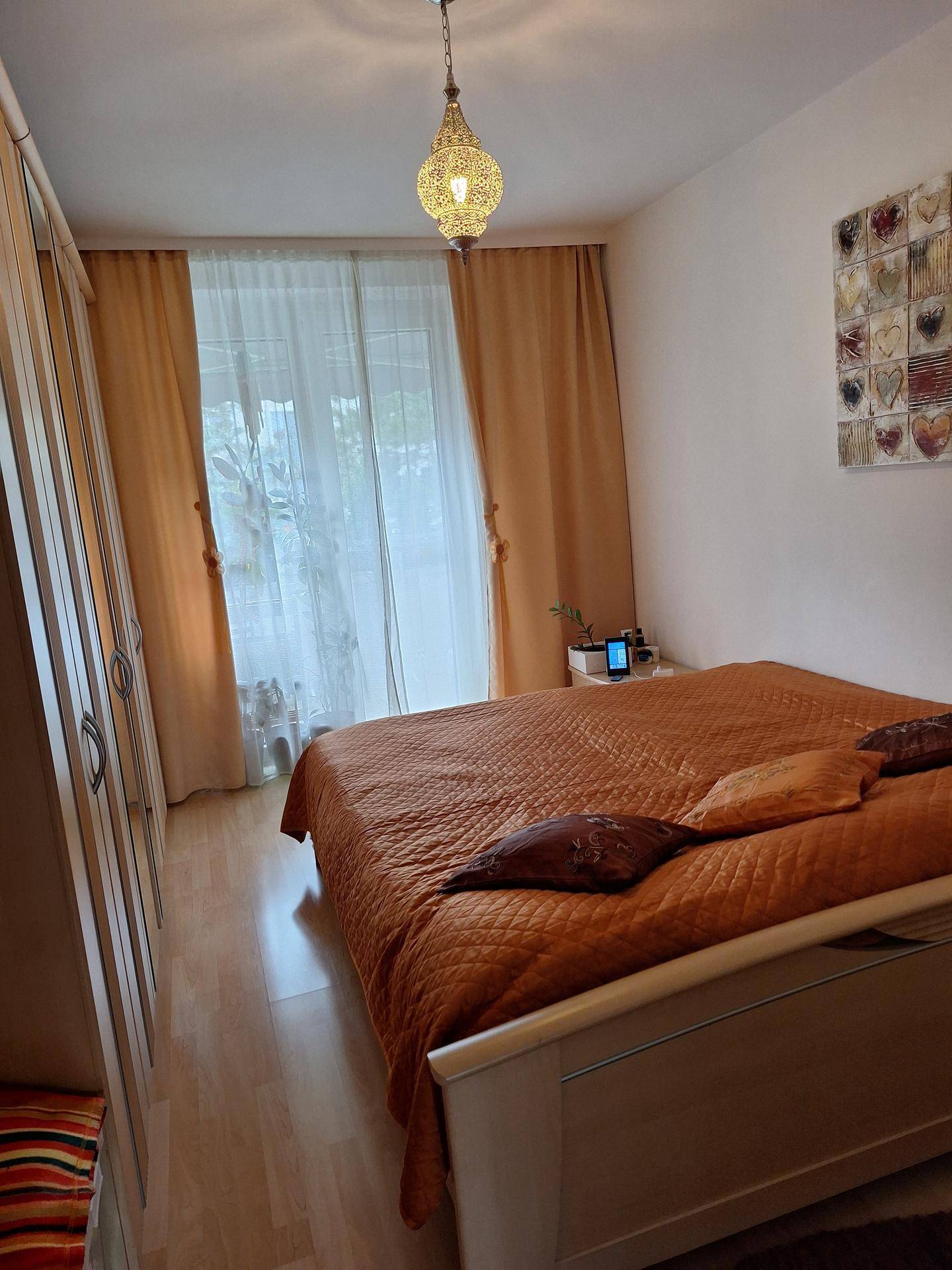 Schlafzimmer mit Doppelbett, Kleiderschrank und Zugang zu einem Balkon.